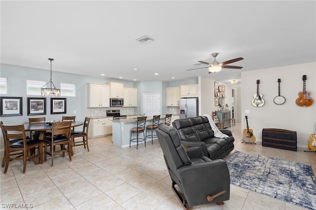 living room with ceiling fan with notable chandelier and light tile floors