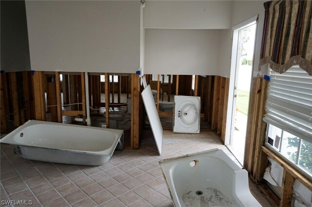 bathroom with plenty of natural light, washer / dryer, and a bathtub