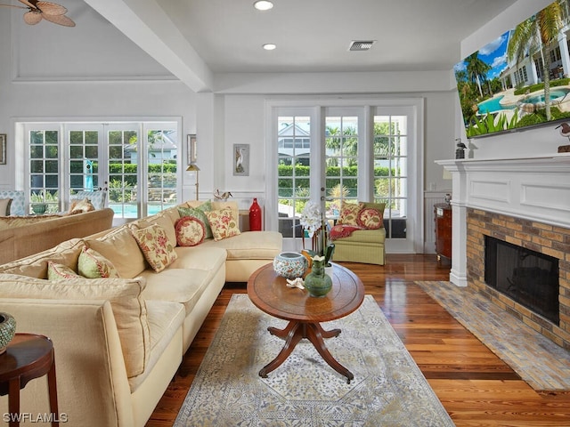 living room with a brick fireplace, dark wood-type flooring, french doors, and a healthy amount of sunlight