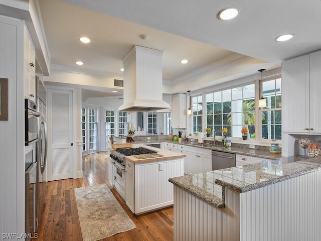 kitchen featuring white cabinetry, island range hood, a center island, kitchen peninsula, and stainless steel appliances