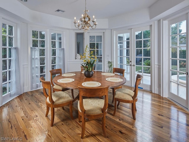 dining area featuring french doors, an inviting chandelier, and light wood-type flooring