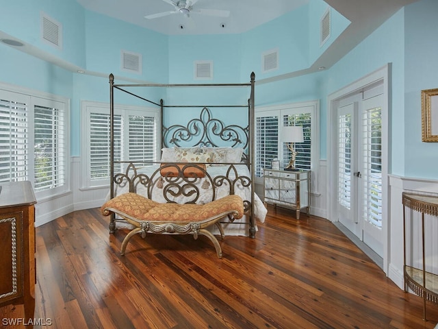 bedroom with ceiling fan, a towering ceiling, access to exterior, and dark hardwood / wood-style flooring