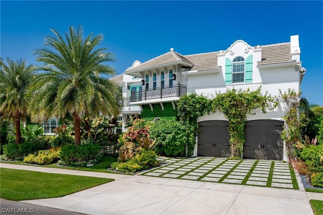 view of front facade featuring a front lawn, a balcony, and a garage