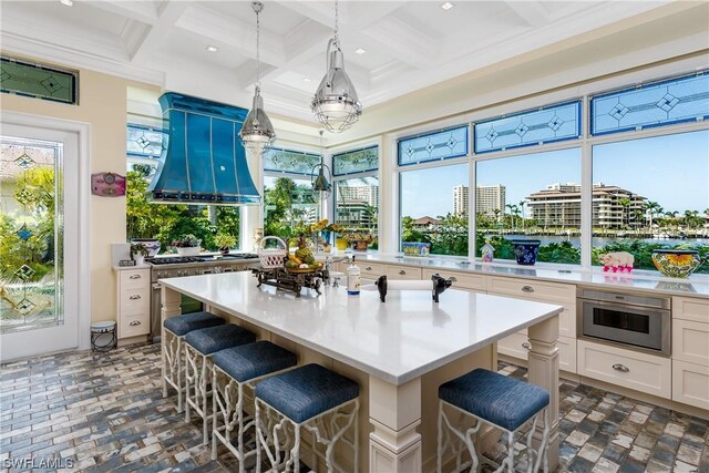 interior space with coffered ceiling, custom exhaust hood, stainless steel oven, and a kitchen island