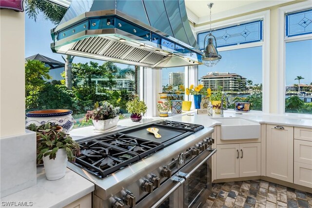 kitchen with double oven range, white cabinetry, premium range hood, ornamental molding, and sink