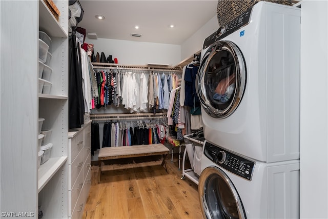 laundry room featuring stacked washer and dryer and light hardwood / wood-style floors