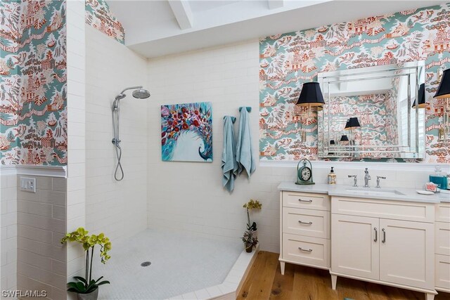 bathroom with beam ceiling, tiled shower, vanity, and hardwood / wood-style flooring