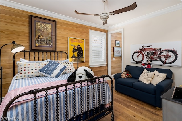 bedroom with ceiling fan, ornamental molding, wood walls, and hardwood / wood-style flooring