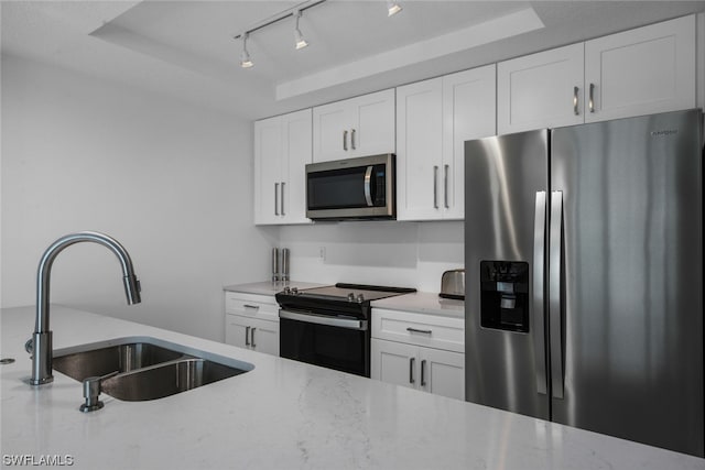 kitchen with white cabinets, a raised ceiling, appliances with stainless steel finishes, and sink