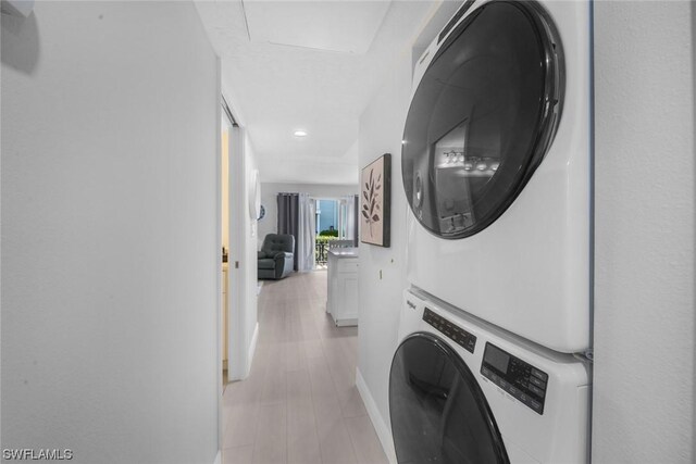 laundry room featuring stacked washer and dryer and light hardwood / wood-style floors