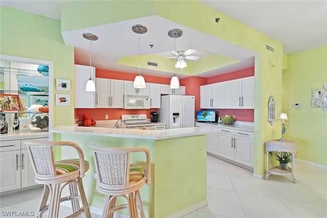 kitchen featuring white appliances, white cabinetry, and a breakfast bar area