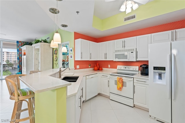 kitchen featuring white cabinetry, sink, kitchen peninsula, white appliances, and a breakfast bar