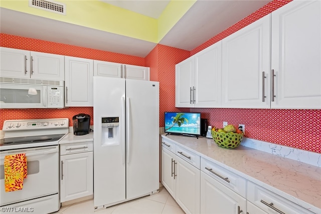 kitchen featuring white cabinets, light stone counters, white appliances, and light tile patterned floors