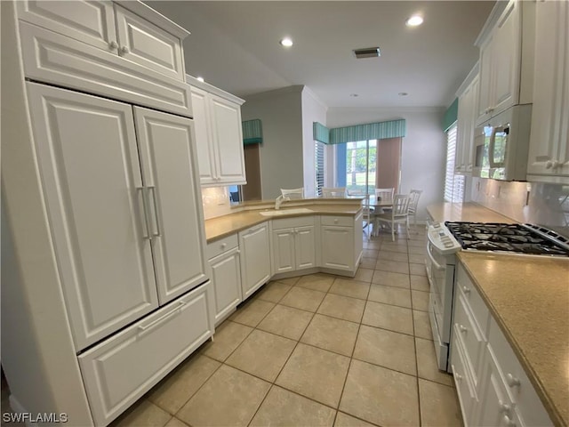 kitchen with light tile patterned flooring, backsplash, white cabinets, and white appliances