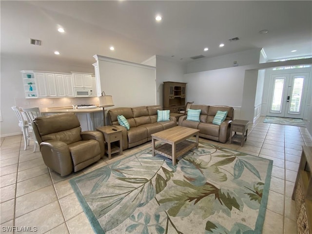 tiled living room with crown molding and french doors