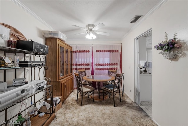 dining area with ceiling fan, light colored carpet, and crown molding