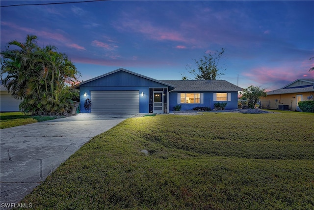 view of front facade with an attached garage, central air condition unit, a lawn, and concrete driveway