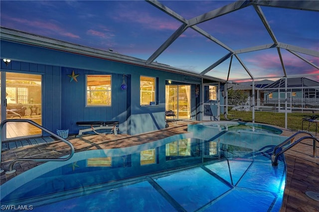 pool at dusk featuring a lanai, a patio area, and an outdoor pool