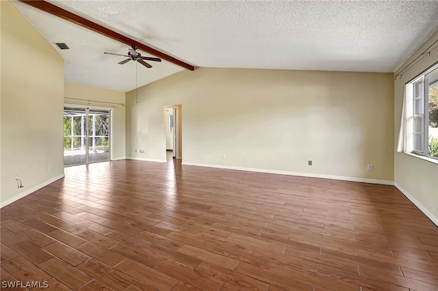 empty room featuring vaulted ceiling with beams, plenty of natural light, and wood finished floors