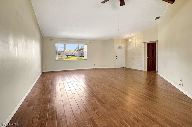 empty room featuring a ceiling fan, visible vents, baseboards, and wood finished floors