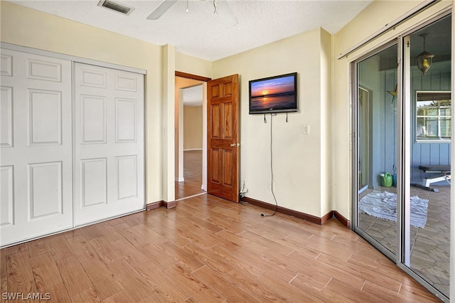 unfurnished bedroom featuring light wood-type flooring, access to outside, visible vents, and a textured ceiling