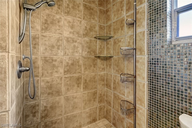 full bathroom featuring tiled shower and toilet