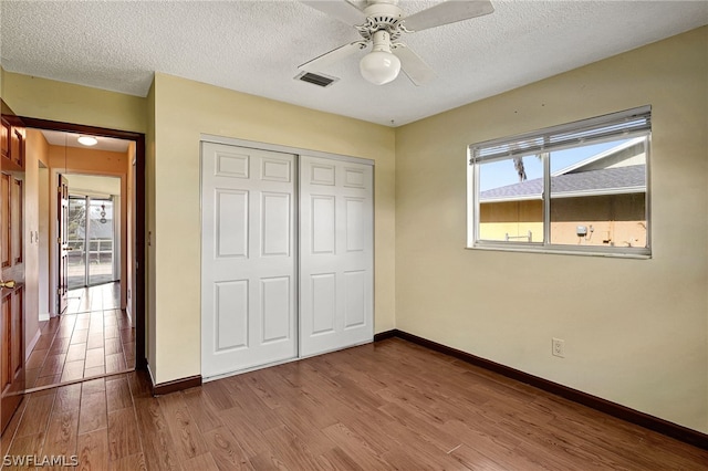 unfurnished bedroom featuring a closet, multiple windows, wood finished floors, and baseboards