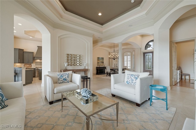 living room featuring a notable chandelier, light tile patterned flooring, a tray ceiling, and crown molding