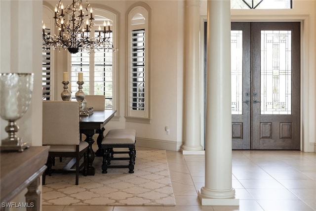 tiled dining room with french doors, a notable chandelier, and decorative columns