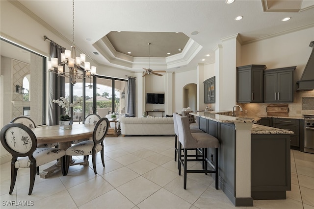 kitchen with kitchen peninsula, a breakfast bar area, backsplash, ceiling fan with notable chandelier, and crown molding