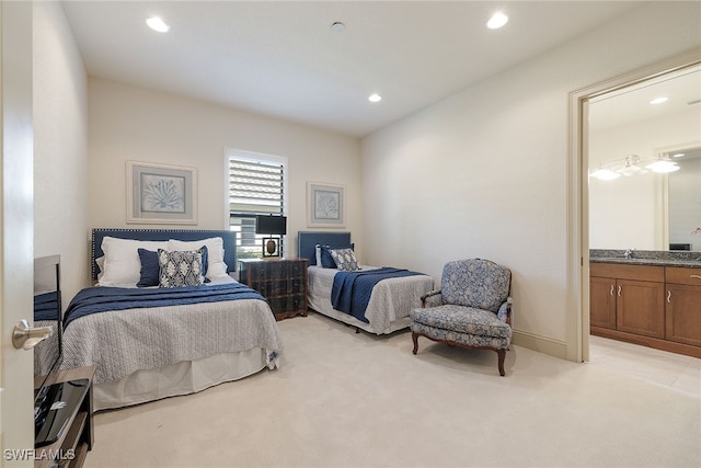 bedroom with sink, light colored carpet, and ensuite bath