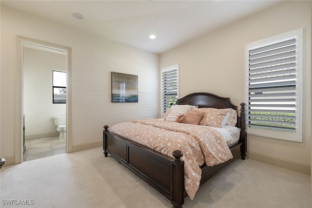 carpeted bedroom with multiple windows and connected bathroom