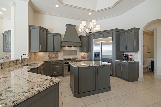 kitchen featuring custom range hood, sink, premium appliances, and light stone counters