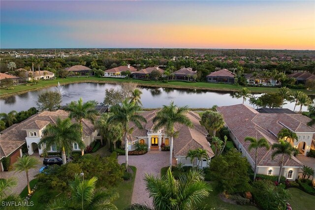 aerial view at dusk featuring a water view