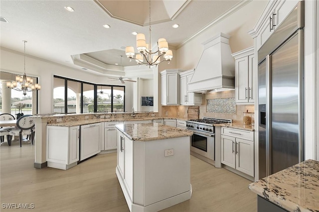 16540 Cellini Ln, Naples, FL 34110 - kitchen featuring ornamental molding, a peninsula, custom exhaust hood, high quality appliances, and light wood finished floors