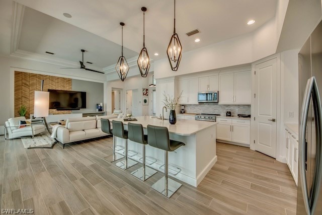 kitchen featuring white cabinets, a kitchen bar, hanging light fixtures, appliances with stainless steel finishes, and ceiling fan