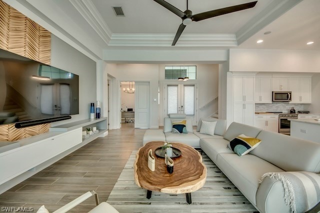 living room featuring ceiling fan with notable chandelier, crown molding, and light hardwood / wood-style flooring