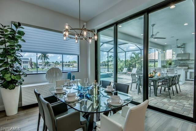 dining area featuring light wood-type flooring and ceiling fan with notable chandelier