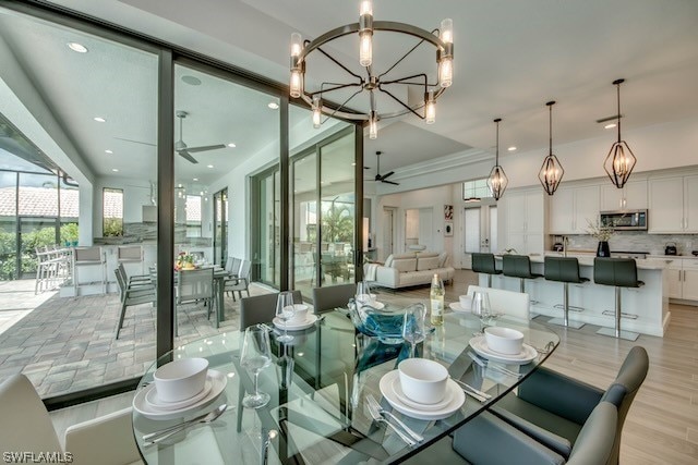 dining room featuring ceiling fan with notable chandelier and light hardwood / wood-style floors