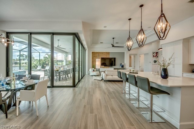 dining area featuring ceiling fan with notable chandelier and light wood-type flooring