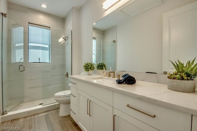 bathroom featuring vanity, a shower with shower door, and toilet