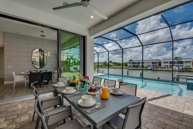 view of patio featuring a water view, glass enclosure, and ceiling fan