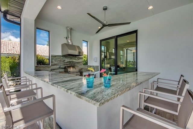 view of patio / terrace featuring ceiling fan, area for grilling, and a bar