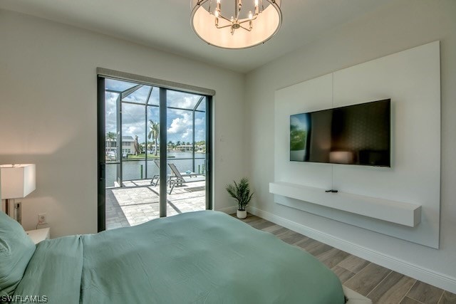 bedroom featuring wood-type flooring, access to outside, and an inviting chandelier