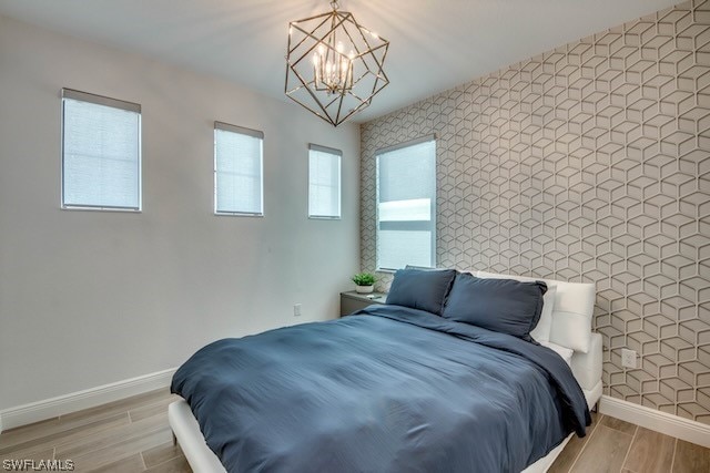 bedroom with light hardwood / wood-style flooring, tile walls, and an inviting chandelier