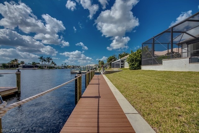 dock area with a lanai, a water view, and a lawn