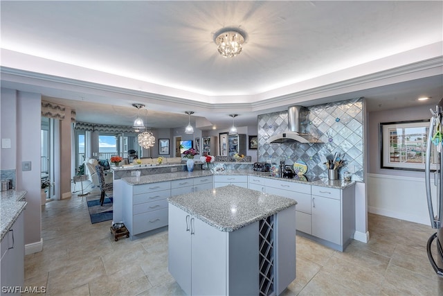 kitchen featuring white cabinets, backsplash, black electric cooktop, wall chimney exhaust hood, and a center island