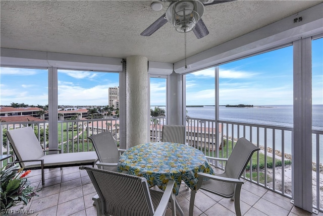 sunroom featuring a water view and ceiling fan