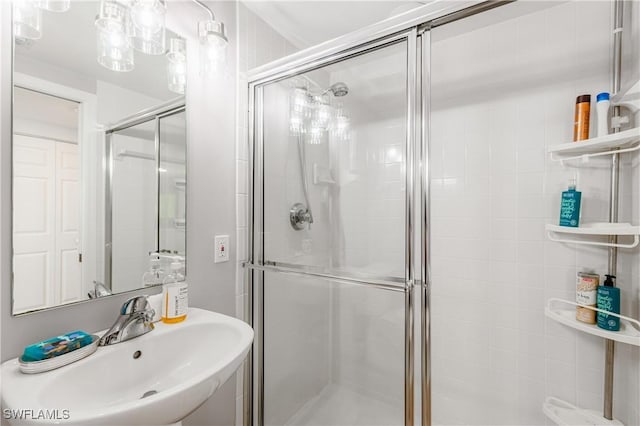 bathroom with a shower with shower door and sink