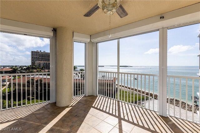 sunroom / solarium featuring a water view, a healthy amount of sunlight, and a view of the beach